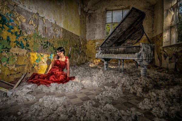 La chica del vestido rojo se sienta al lado del piano