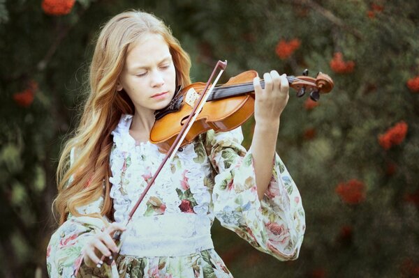 Fille en robe florale joue du violon