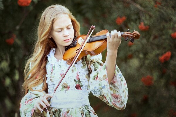 Ragazza in abito floreale suona il violino