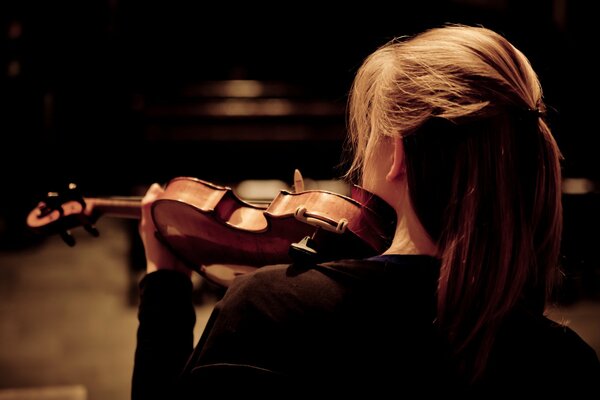 The girl plays the violin. Rear view