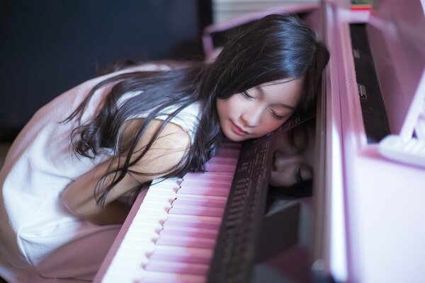 A girl sleeps on the piano keys