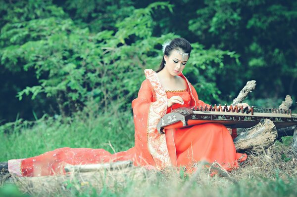 Mädchen, das ein asiatisches Musikinstrument spielt