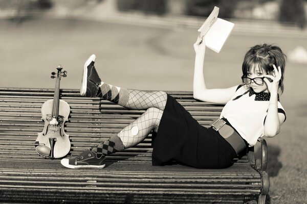Mädchen liegt auf einer Bank mit einer Geige
