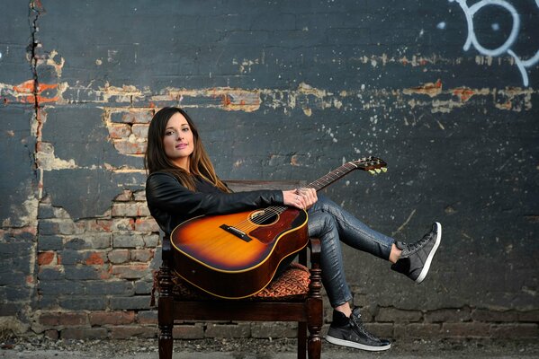 Photo of a girl with a guitar on a wall background