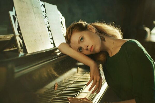 The girl leaned thoughtfully on the piano