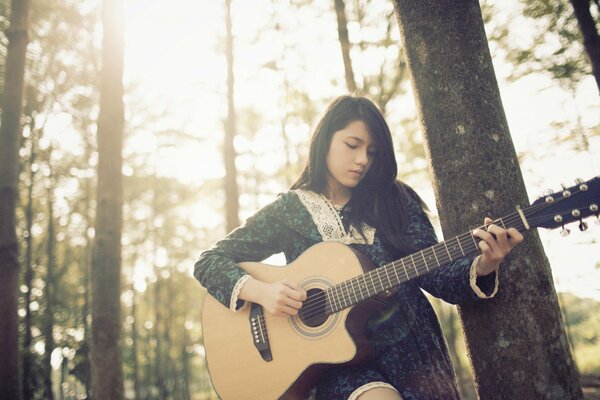 Girl playing guitar in the woods