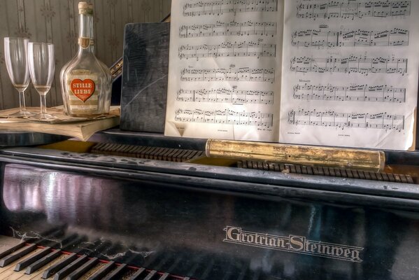 Piano with sheet music and a bottle on it