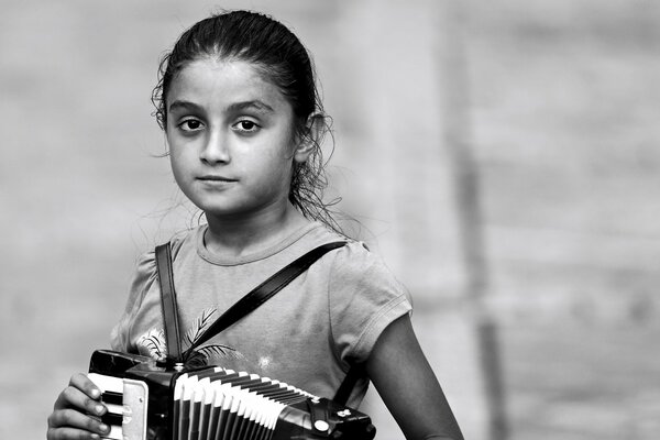 Foto en blanco y negro de una niña con un acordeón en sus manos