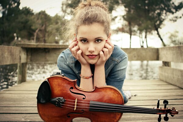 A girl with a violin in autumn on the pier