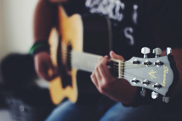 Mani che pizzicano le corde su una chitarra acustica