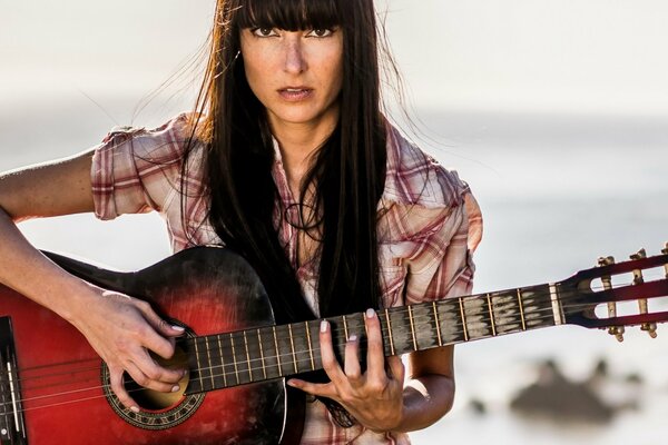 Fille avec une guitare sur le rivage