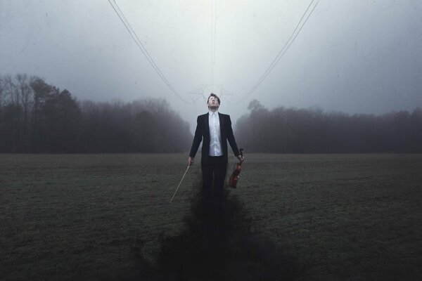 Violinist with his violin on the background of an autumn field