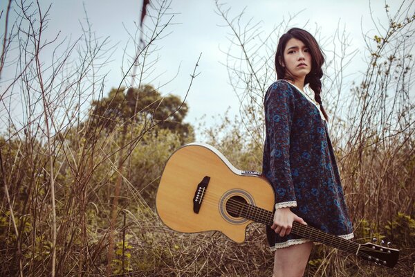 Fille avec guitare sur fond de nature