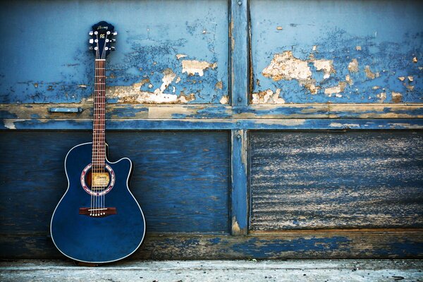 Синяя гитара на фоне облезлой стены