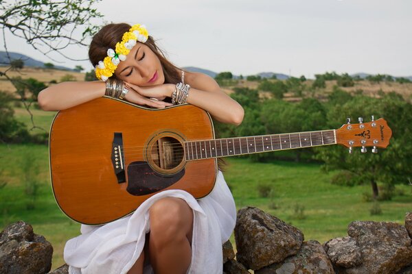 Beautiful girl in a wreath with a guitar