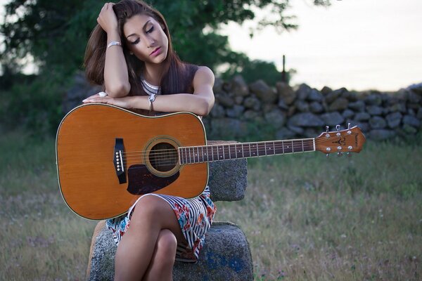 Hermosa chica en el campo con una guitarra