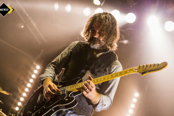 Photo of a bearded guitarist in the spotlight