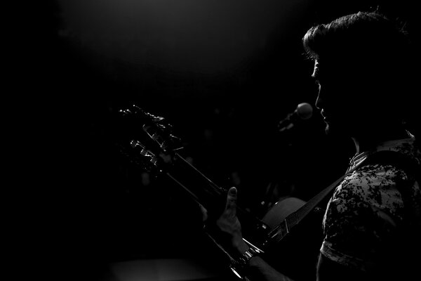 Piosenkarz z gitarą w czarnej ciemności