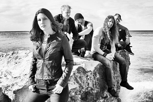 Delain group on the shore sitting on the rocks