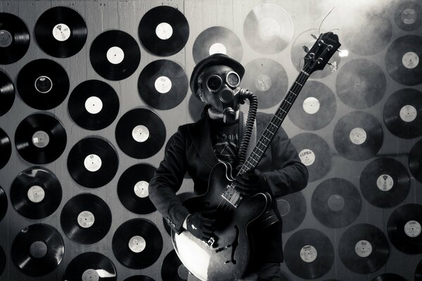 A male musician in a gas mask plays the guitar