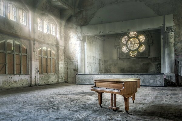 An old grand piano in the hall with a stained glass window