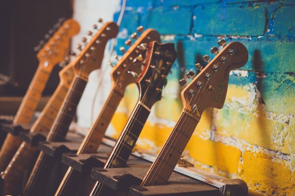 Diapasones de guitarras sobre un fondo de pared de ladrillo azul y amarillo