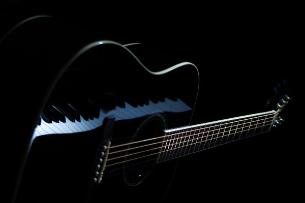 Die Tasten des Flügels spiegeln sich in der schwarzen Gitarre wider