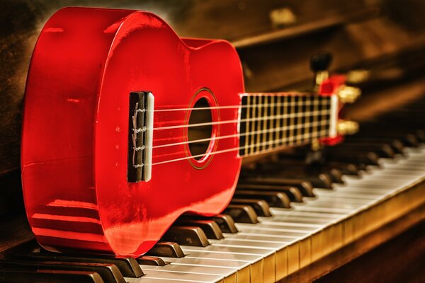 La chitarra si trova su un pianoforte che suona musica di colore rosso