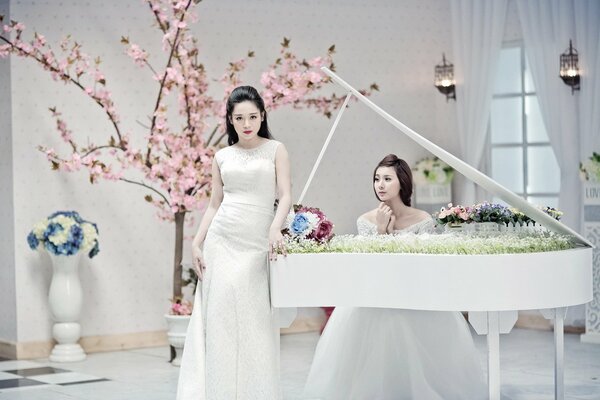 Girls in white dresses next to the piano