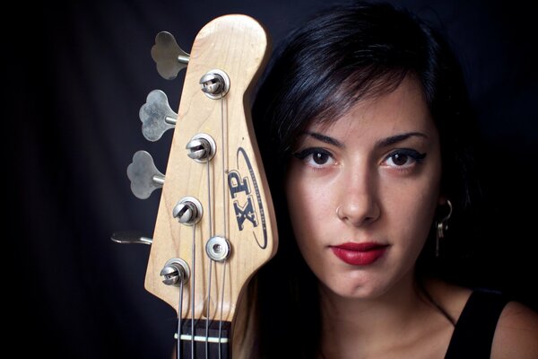 Cara de niña con diapasón de guitarra sobre fondo negro