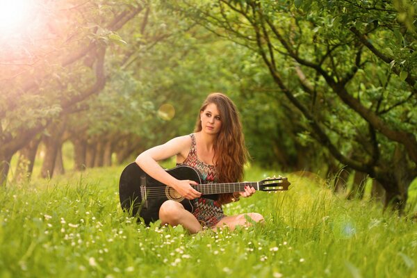 Dziewczyna gra na gitarze na zielonej polanie