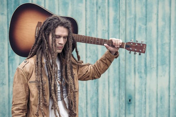 A young man with a guitar on his shoulder