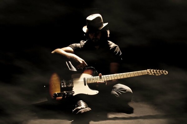 A musician plays guitar in the shade