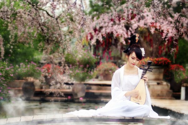 A young girl plays a musical instrument in the garden