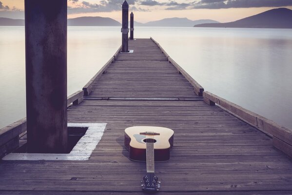 Гитара лежит на длинном деревянном мосте