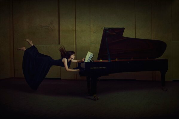 La ragazza in un vestito nero prende il volo da un pianoforte a coda