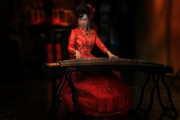 Восточная красавица в красном платье играет на Гуцинь