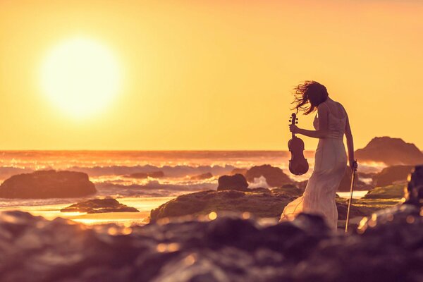 A girl playing the violin on the seashore