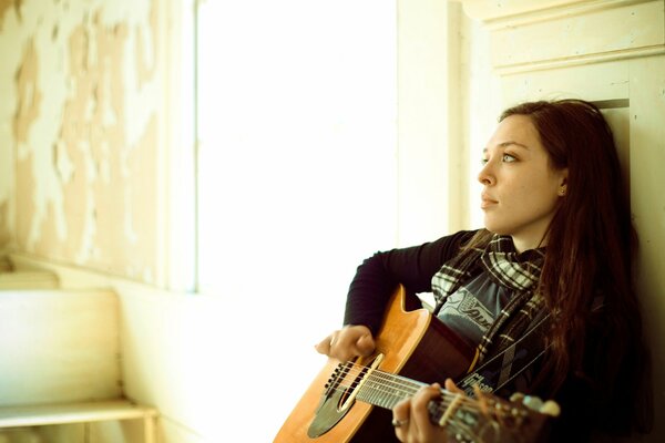 Певица Карли Гибсон сидит с гитарой