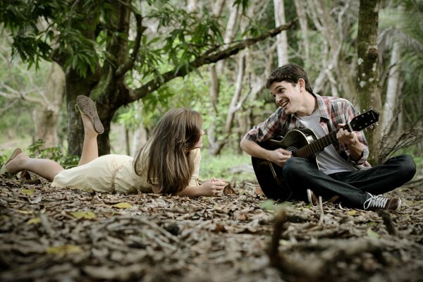 Mec joue de la guitare fille dans les bois