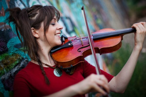 Lindsey Stirling suona il violino sullo sfondo di un muro di graffiti