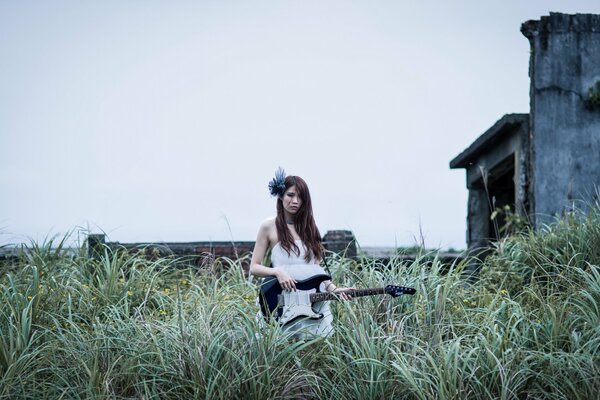 A girl with a guitar in the tall grass