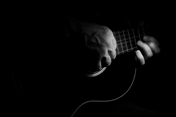 Hand on guitar strings in the dark