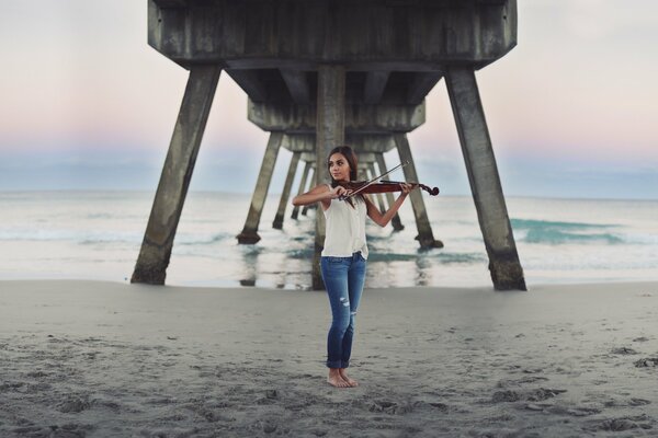 Девушка на берегу моря играет на скрипке