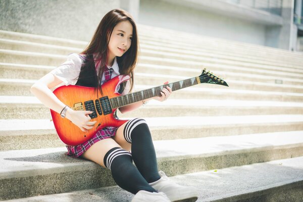 Schoolgirl in knee socks with a guitar in her hands