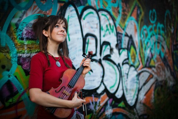 Bellezza con violino sullo sfondo di un muro dipinto