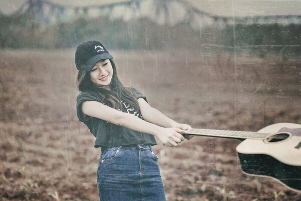 Chica asiática con la guitarra en el campo