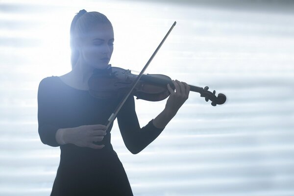 Chica tocando el violín en la luz