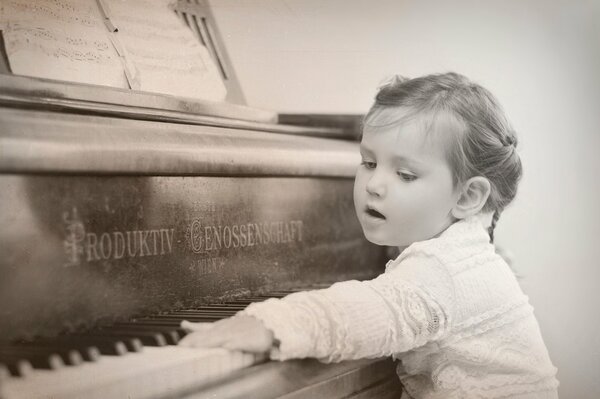 Little girl presses piano keys