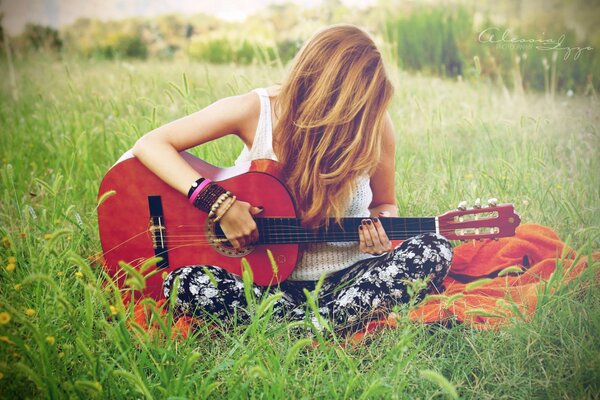 A girl plays guitar in a field